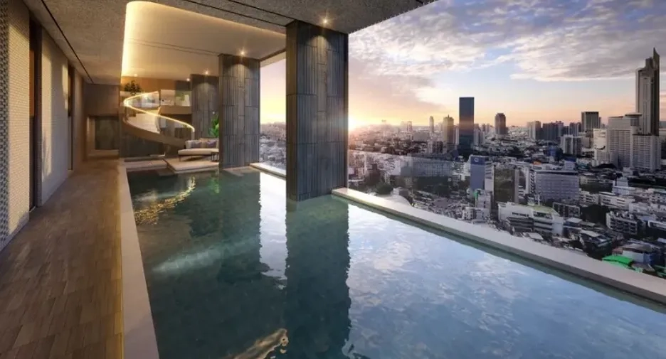 Indoor infinity pool in a luxury Bangkok condo with panoramic sunset views of the city skyline.