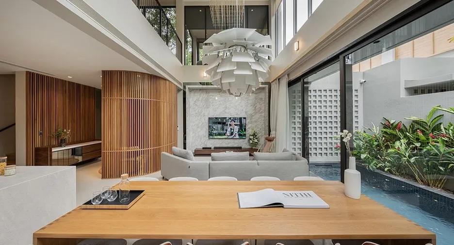 Modern living and dining area of a BKK house at Baanbaan Vibhavadi 20 with floor-to-ceiling windows and stylish decor.