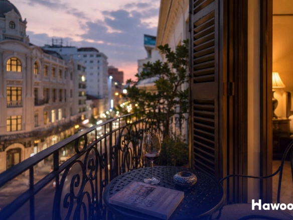Luxury hotel balcony overlooking a historic city district in Southeast Asia at sunset, highlighting tourism and real estate growth.