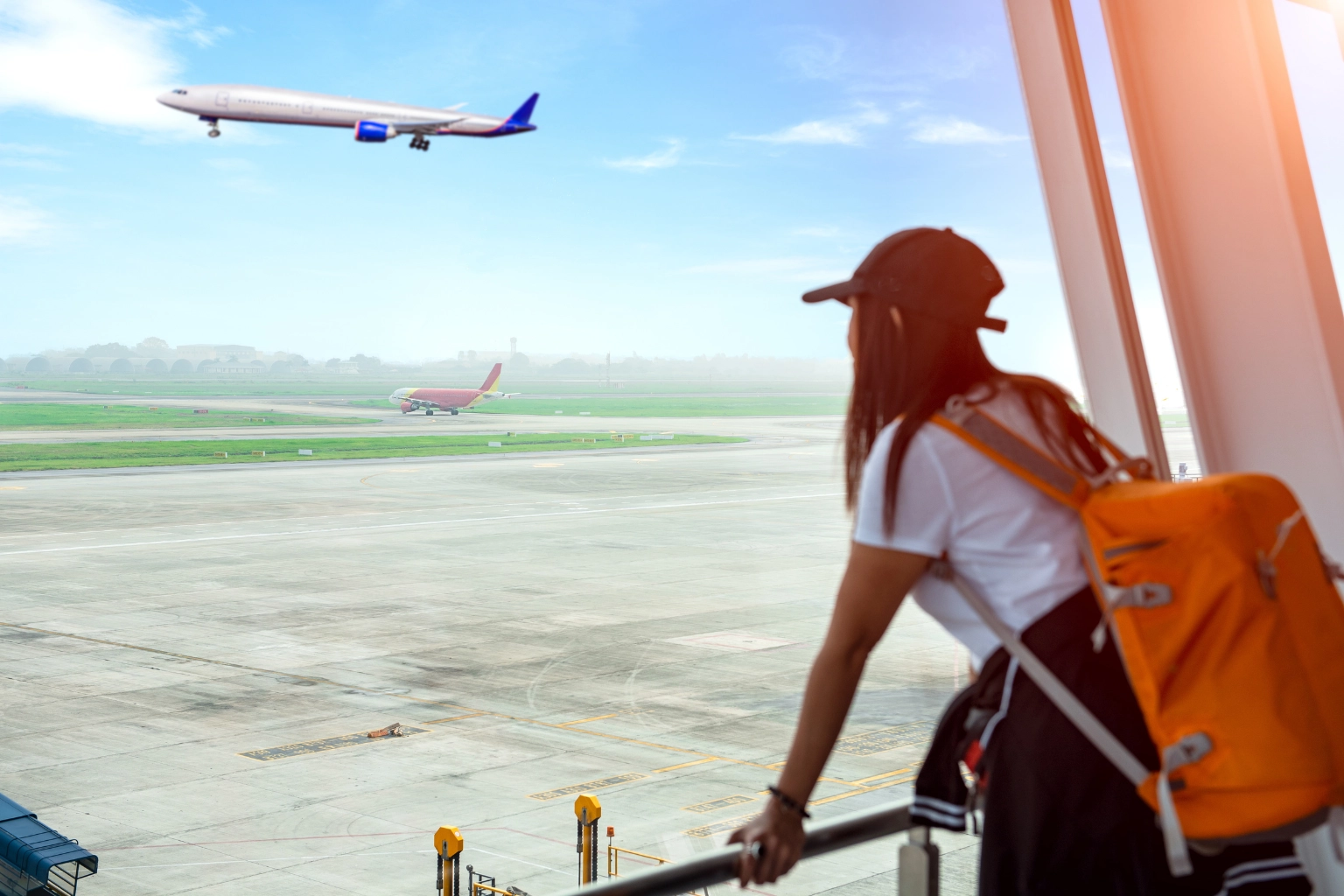 Traveler at airport watching airplane departure illustrating long haul travel trends in Southeast Asia property market